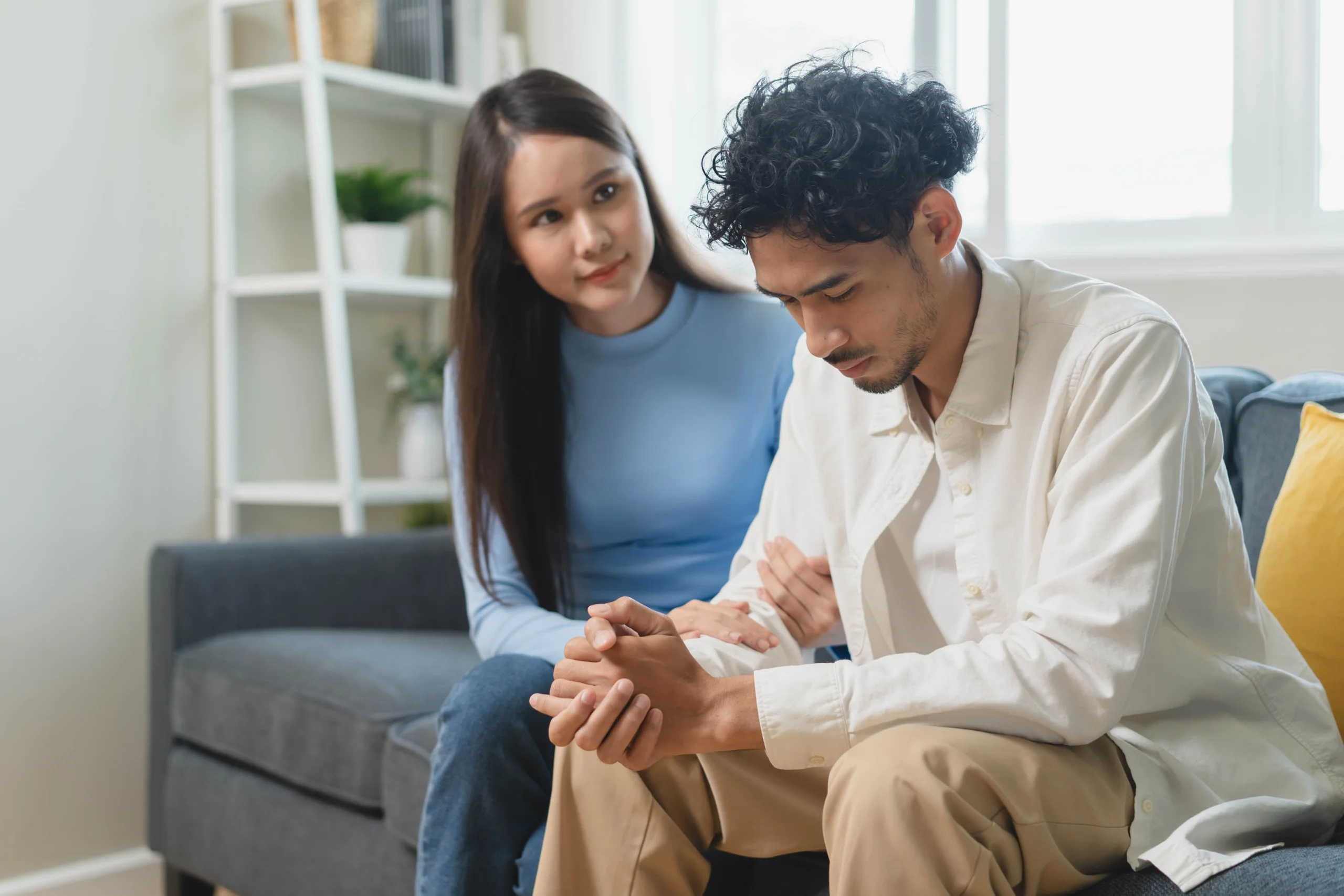 woman consoles man while sitting on a couch talking about alcohol addiction treatment