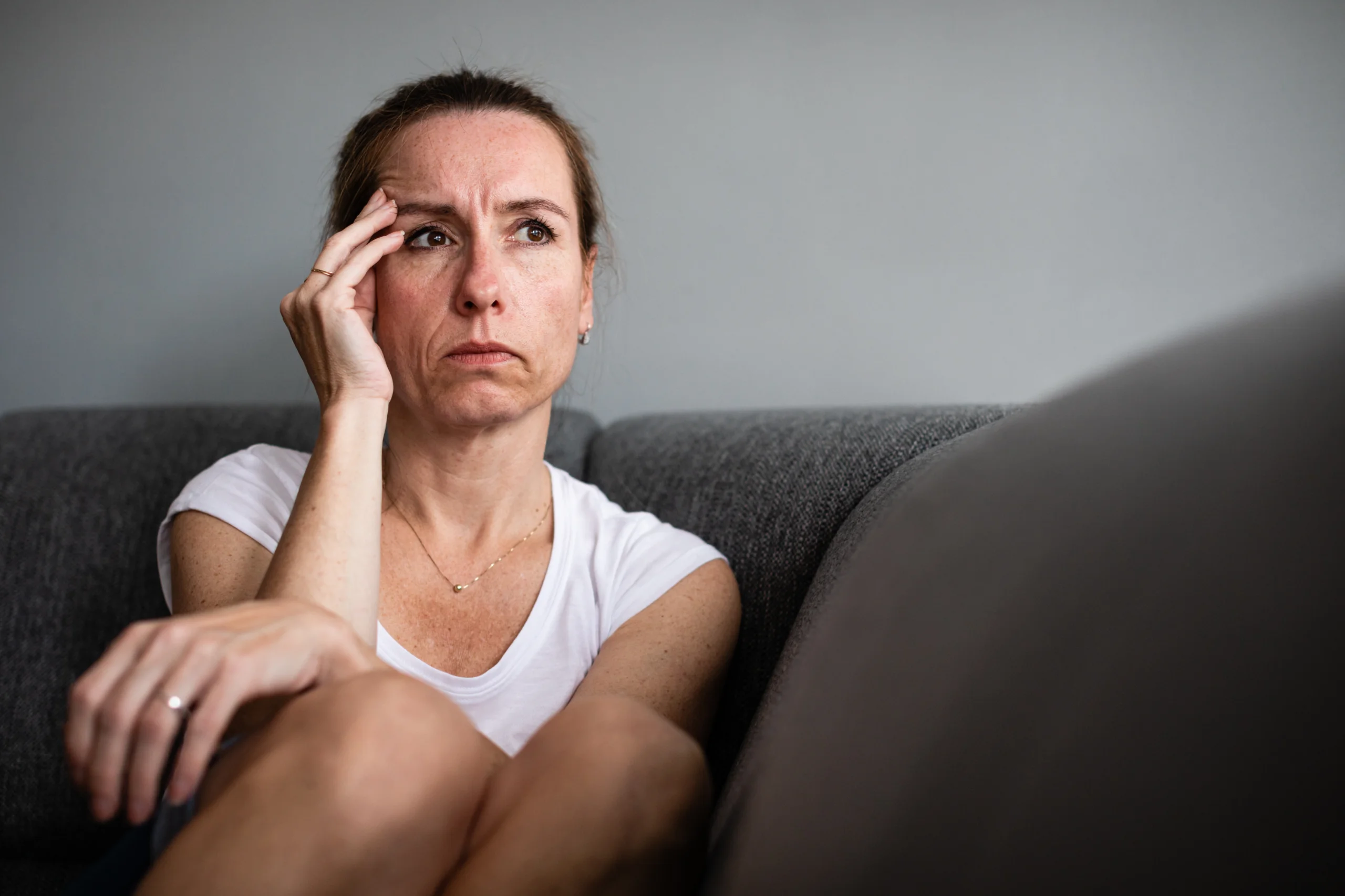 woman with headache holds hand to temple thinking about fentanyl addiction symptoms