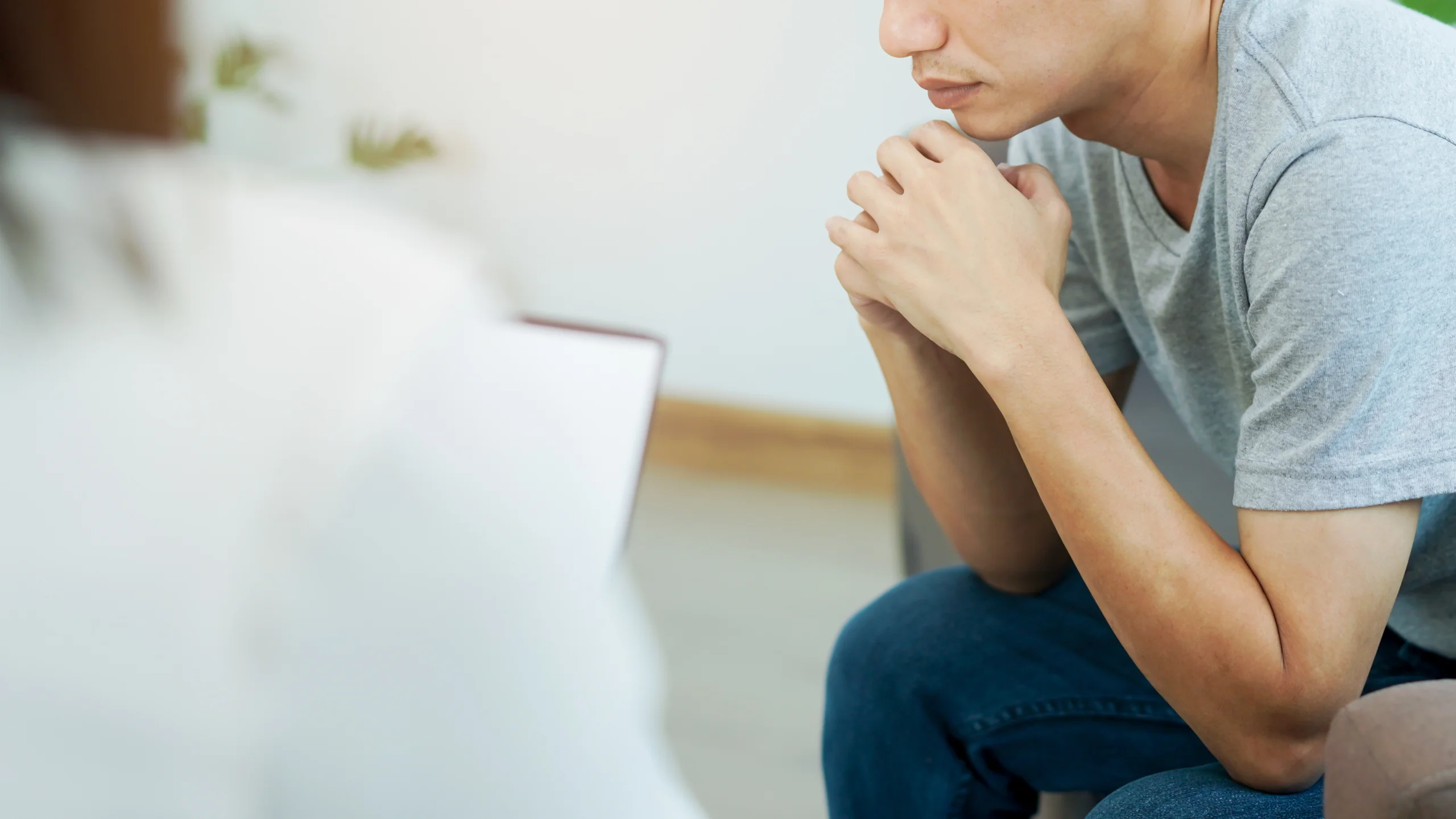 person sits and leans over thinking hard about signs of heroin addiction