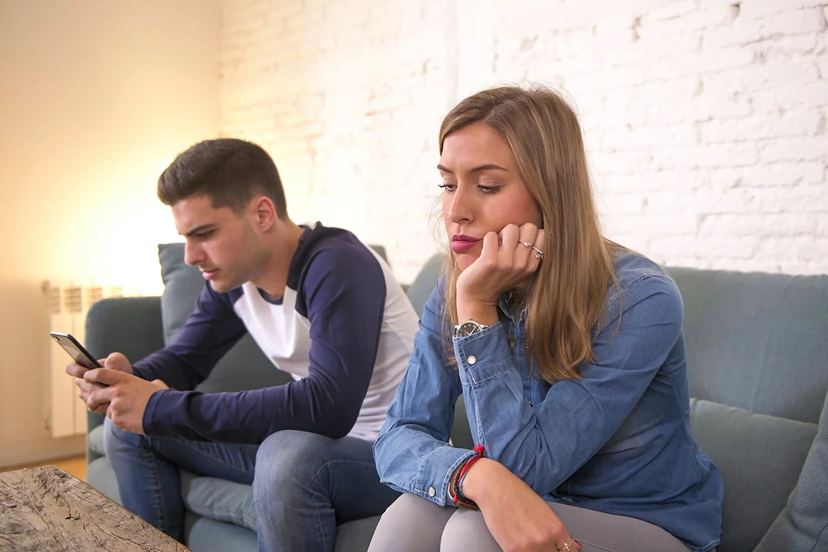 Couple sitting together, looking concerned about man showing signs of gaming addiction
