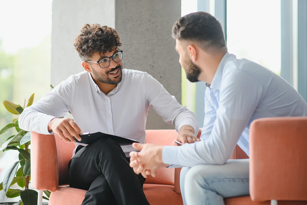 Two men discussing in a modern setting about kratom use and risks